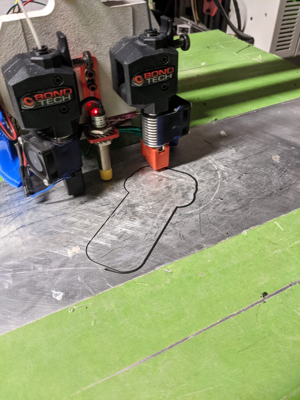 Bondtech dual extruders mounted above a green print bed