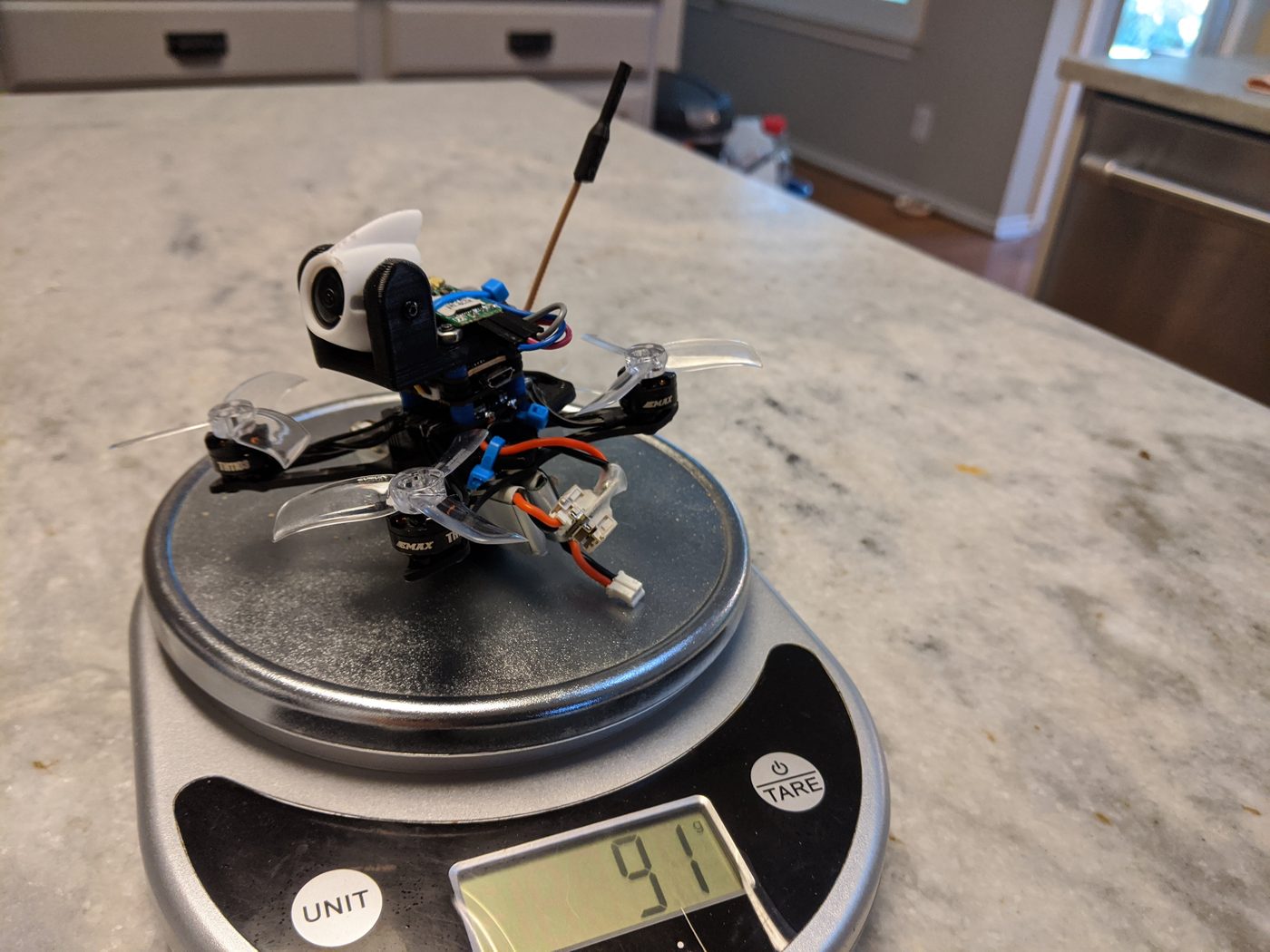 Micro FPV quadcopter on a kitchen scale reading 91 grams